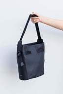 Black leather handbag with small Spixal logo in silver held by a hand against a white background
