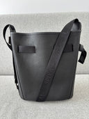 Black pebble leather handbag with Spixal logo embossed jacquard webbing shoulder strap on a light grey background
