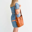 Woman wearing a denim dress with a brown leather bag and a spixal logo on a light background