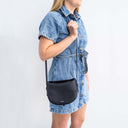 Fleur Saddle Leather Crossbody Handbag Black — Shoulder carry by women in denim dress | Spixal
