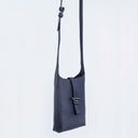 Black leather crossbody bag with small Spixal logo on a light grey background