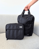 Black laptop backpack and lunch bag with a visible Spixal logo on a light gray surface.