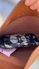 Phone with a floral case in a tan bag