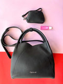 Black leather handbag with a smaller black handbag on a pink and red background