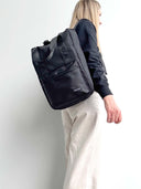Person wearing a black backpack with Spixal logo on a webbing strack against a white background